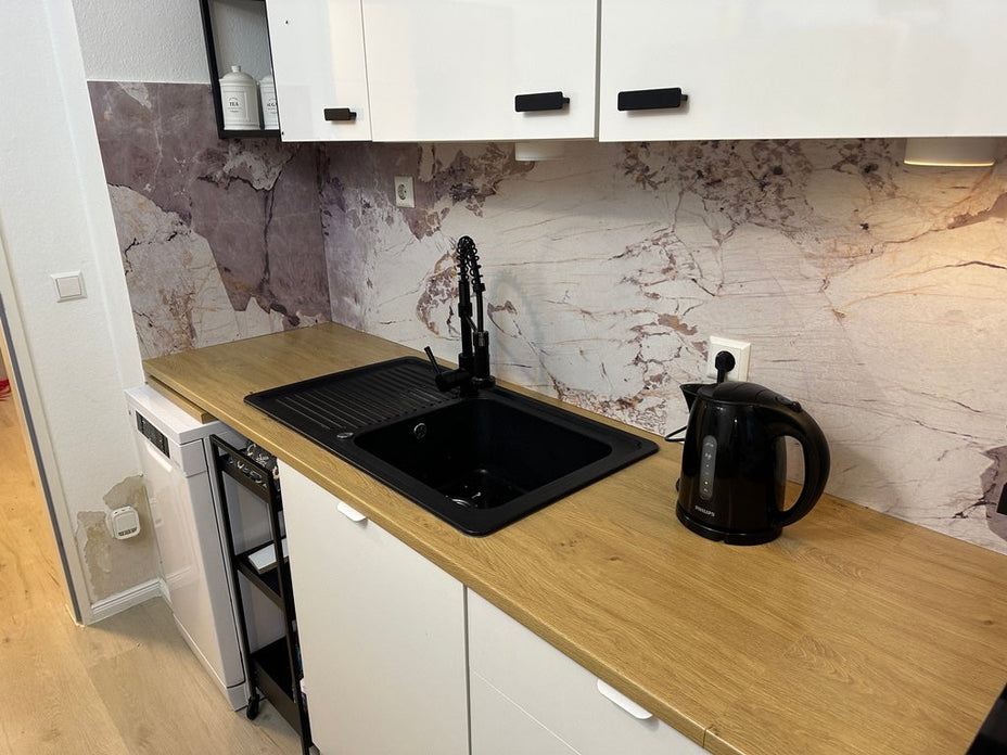 Ściana nad blatem kuchennym wyłożona panelem PVC Patagonia Quartzite, ze zlewem i gniazdkiem